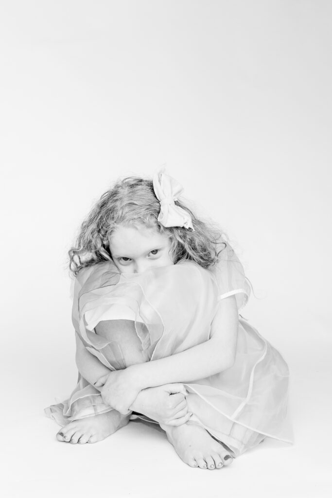 black and white picture of girl sitting on ground with knees up looking at the camera during a personality portrait party with 5U Photography