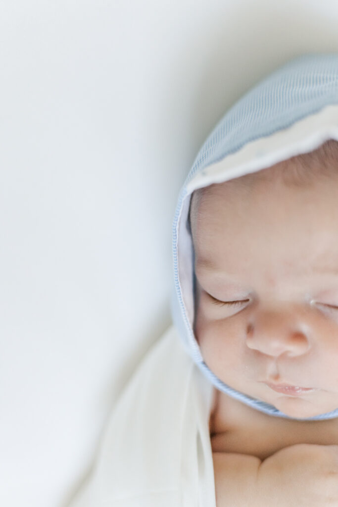 Close-up of newborn baby boy’s face, showing delicate toes and soft skin, taken during a winter in-home newborn session.