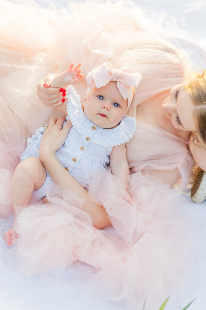 Baby sitting up on a soft blanket in a boho field near Birmingham, Alabama, smiling and enjoying the warm sunlight during their 6-month milestone session with 5U Photography.