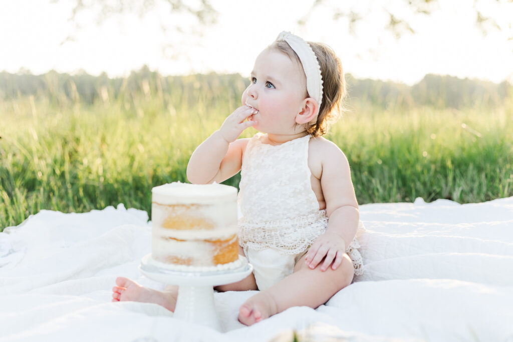 1 year old little girl tasting her smash cake at session with 5U Photography