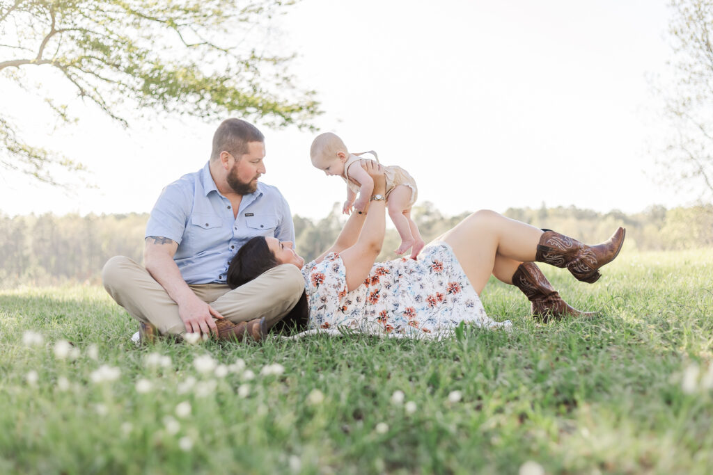 Family laying on blanket surrounded by wildflowers during 6 month session with 5U Photography in field outside of Birmingham, Alabama