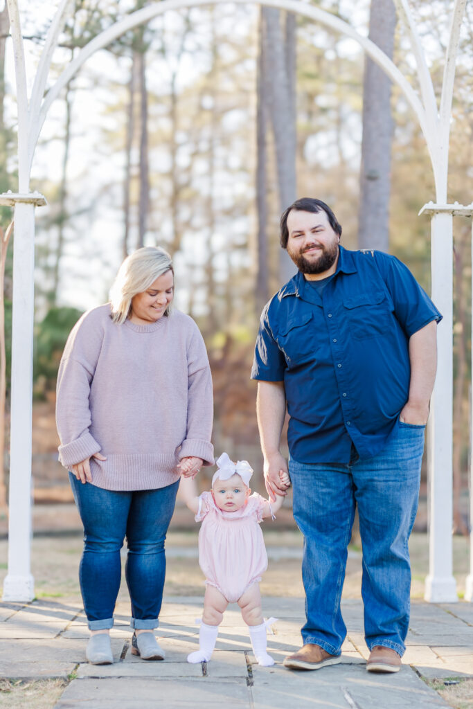 Miss Maggie’s family walking hand-in-hand through Birmingham Botanical Gardens during a 12-month milestone family session by 5U Photography.