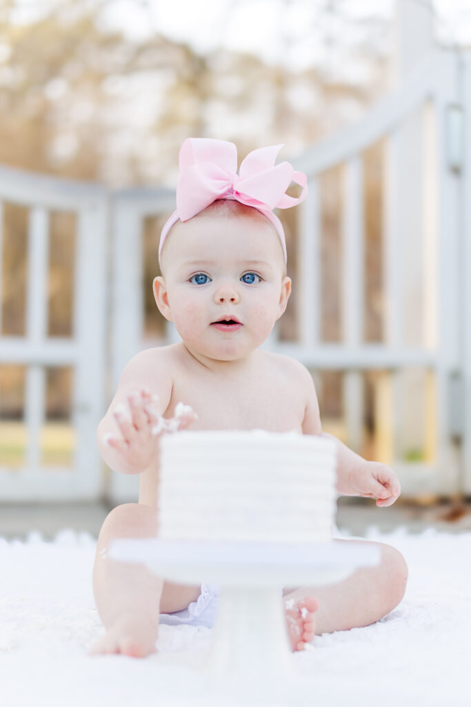 Miss Maggie enjoying her smash cake during her 12-month milestone photoshoot at Birmingham Botanical Gardens, captured by 5U Photography