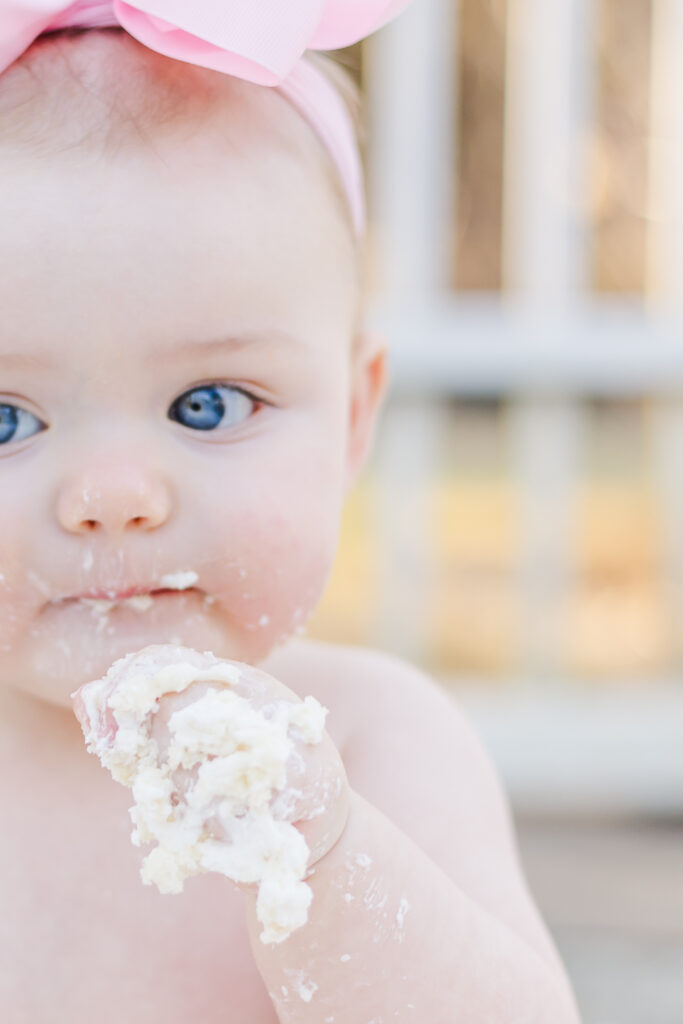 Close up of baby girl eating smash cake during 12 month milestone photo session