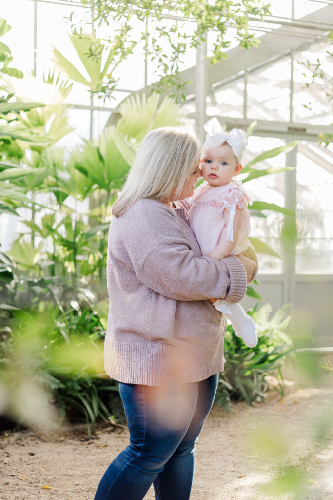 mom holding one year old little girl during 12 month milestone membership session at the birmingham botanical gardens 