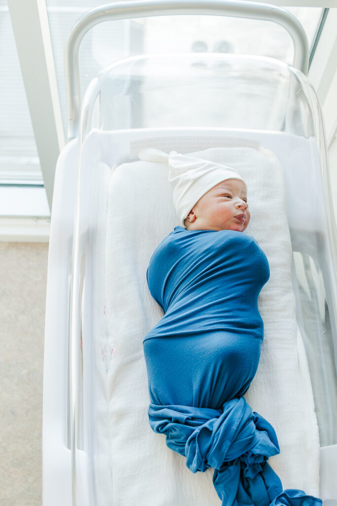 newborn baby boy laying in hospital crib next to window with beautiful natural light during Birmingham AL Fresh-48 session with 5U Photography