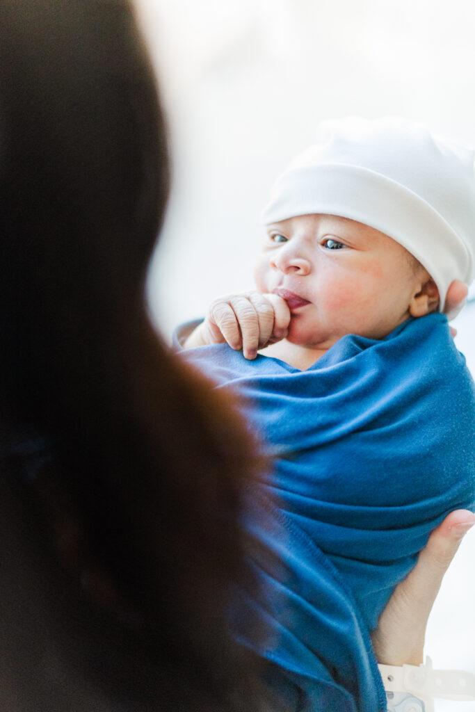 Mom Kinsley lovingly gazing at newborn baby Ezra, captured during his Fresh 48 photoshoot