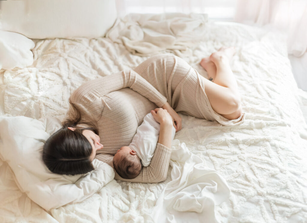 Mom lying on her side cradling her newborn baby boy during a cozy in-home newborn session in Birmingham AL with 5U Photography