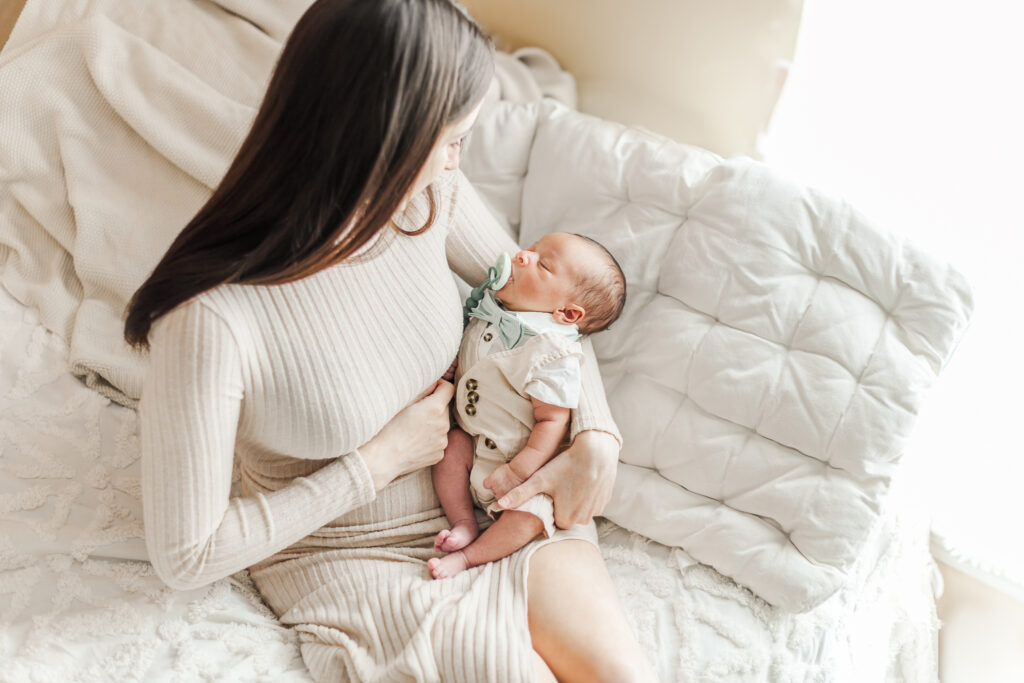 Mom Kinsley holding newborn baby Ezra in a soft, cozy blanket during their in-home newborn photoshoot