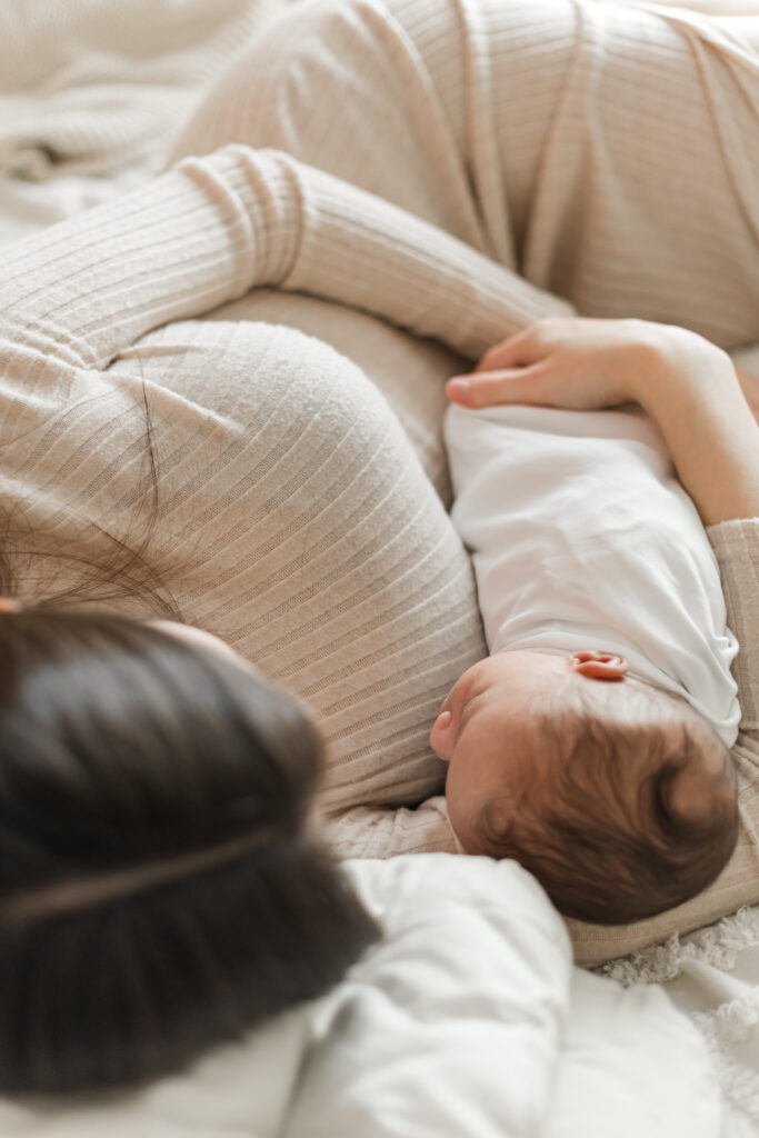 mom lying with newborn baby boy during cozy in-home newborn session