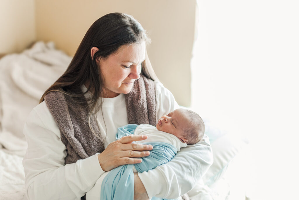 Grandmother Nonni lovingly holding newborn baby Ezra during their family newborn photoshoot