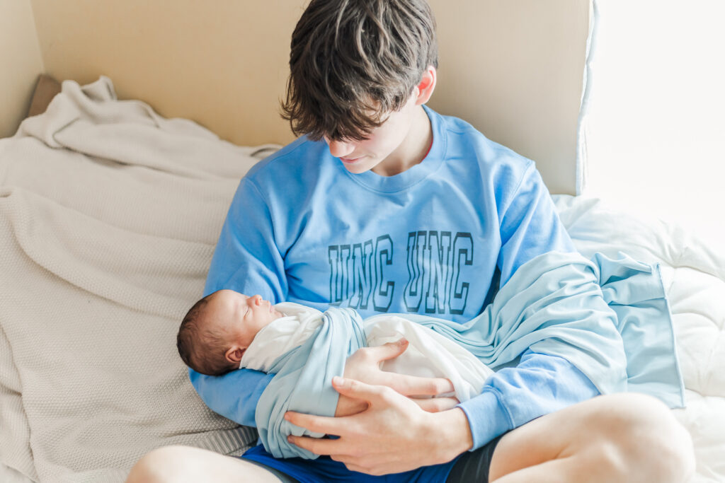 Uncle 'Unc Unc' smiling at newborn baby Ezra, capturing a joyful family moment in their in-home session