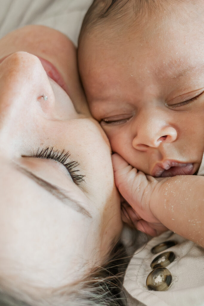 close up of newborn baby boy's face lying cheek to cheek with his mom