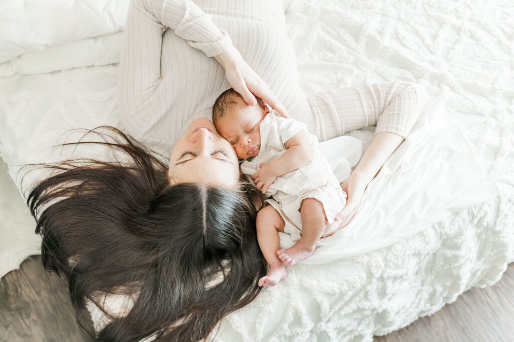 Newborn baby Ezra peacefully sleeping in his mother's arms during an intimate newborn session