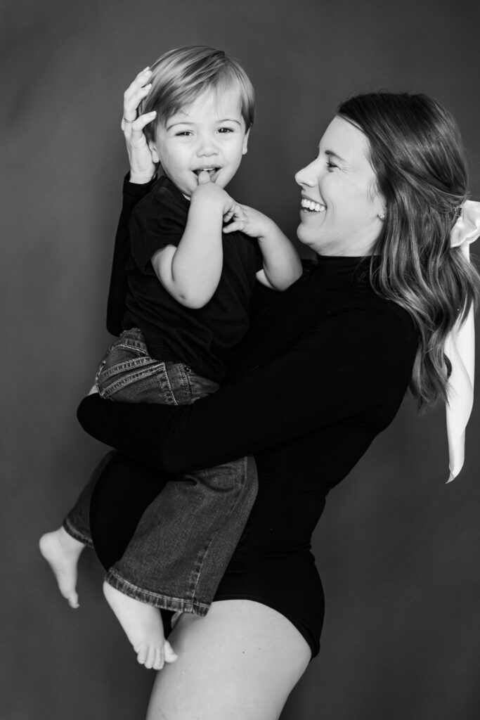 Mom stroking toddler son's hair and laughing during an in-home maternity session in birmingham alabama