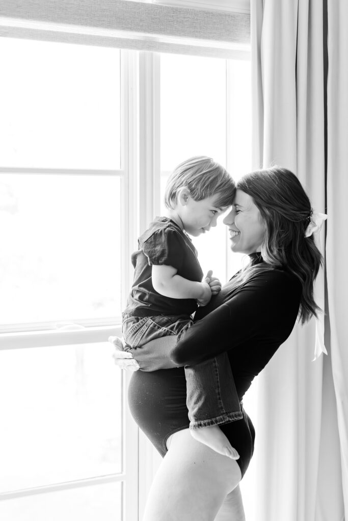 black and white picture of mom standing holding her toddler son forehead to forehead during photo session in Birmingham, AL 