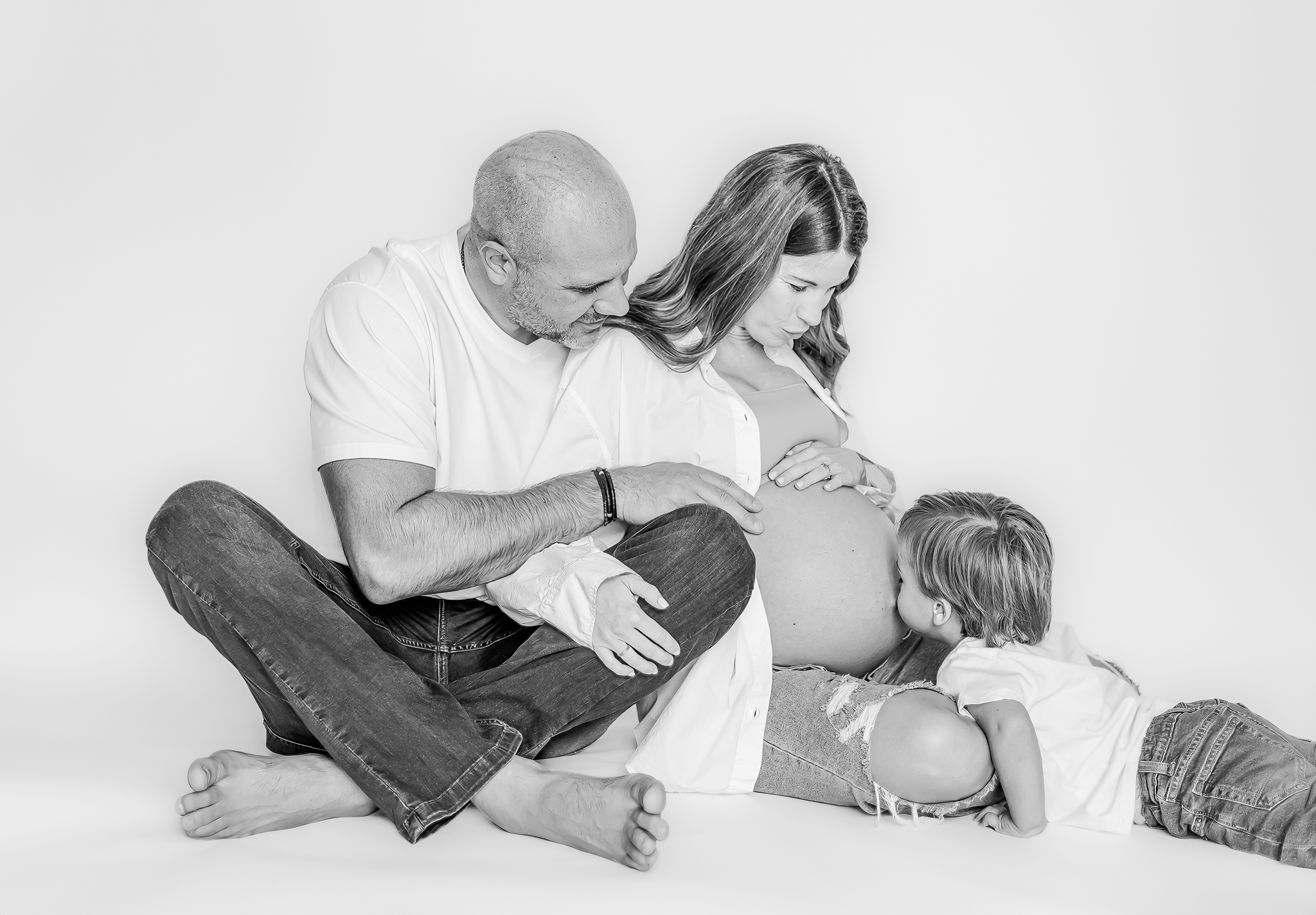 The Lavender family’s firstborn gently kissing the expecting mother's baby bump, with soft lighting creating a peaceful and loving atmosphere in their Birmingham home.