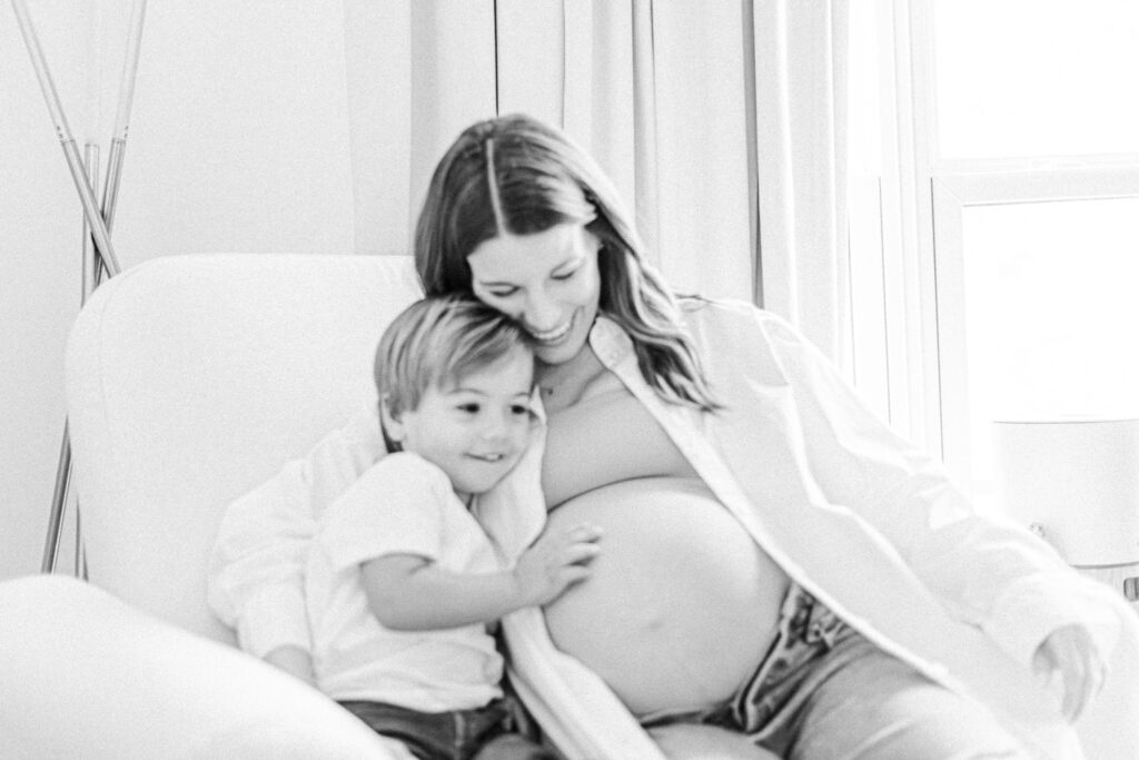 black and white image of boy with hand on expecting mom's baby bump during in-home maternity session with 5U Photography