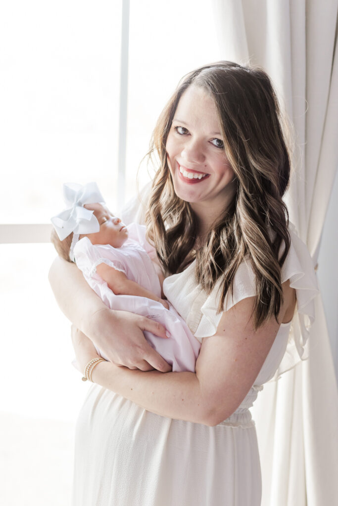 Mom holding baby girl smiling at camera during photo session with 5U Photography