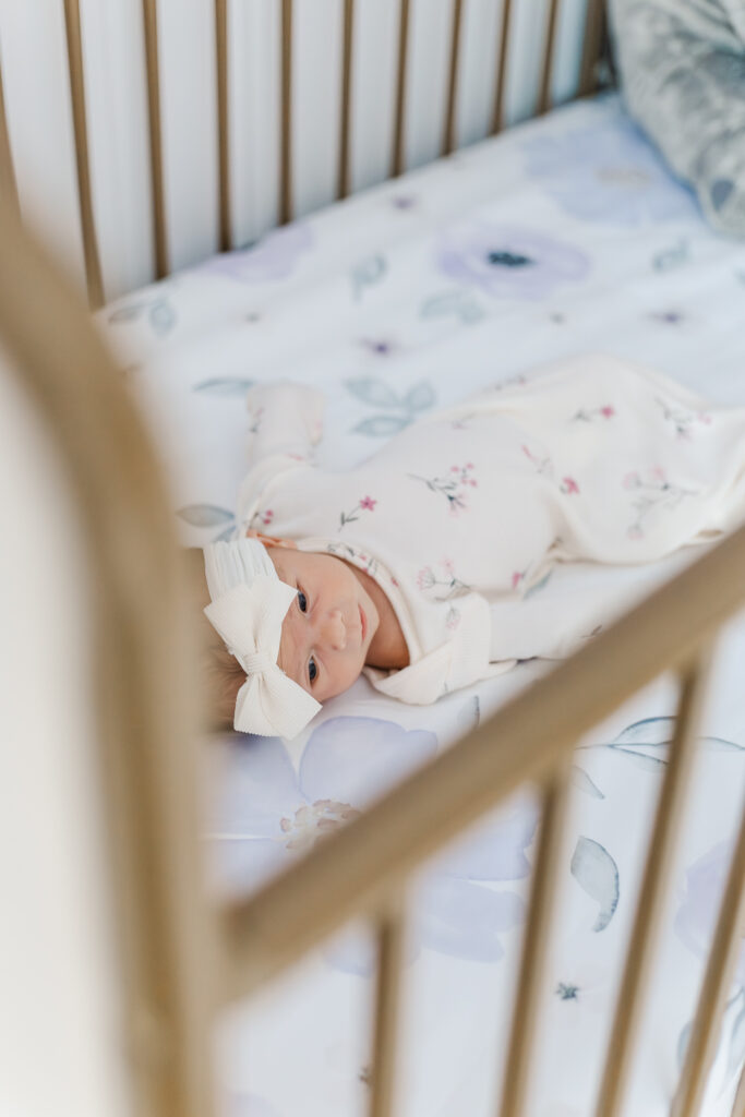 newborn baby girl laying in crib on flowered sheet in family's home