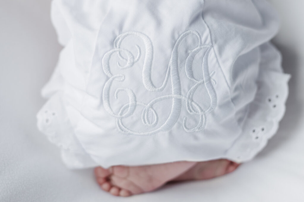 close up picture of baby girls monogrammed bloomers with tiny feet sticking out 