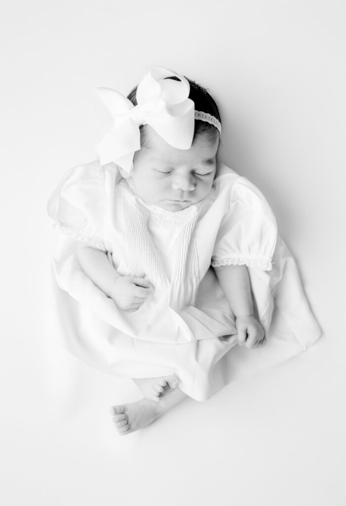 black and white picture of sweet newborn baby girl laying on blanket sleeping peacefully