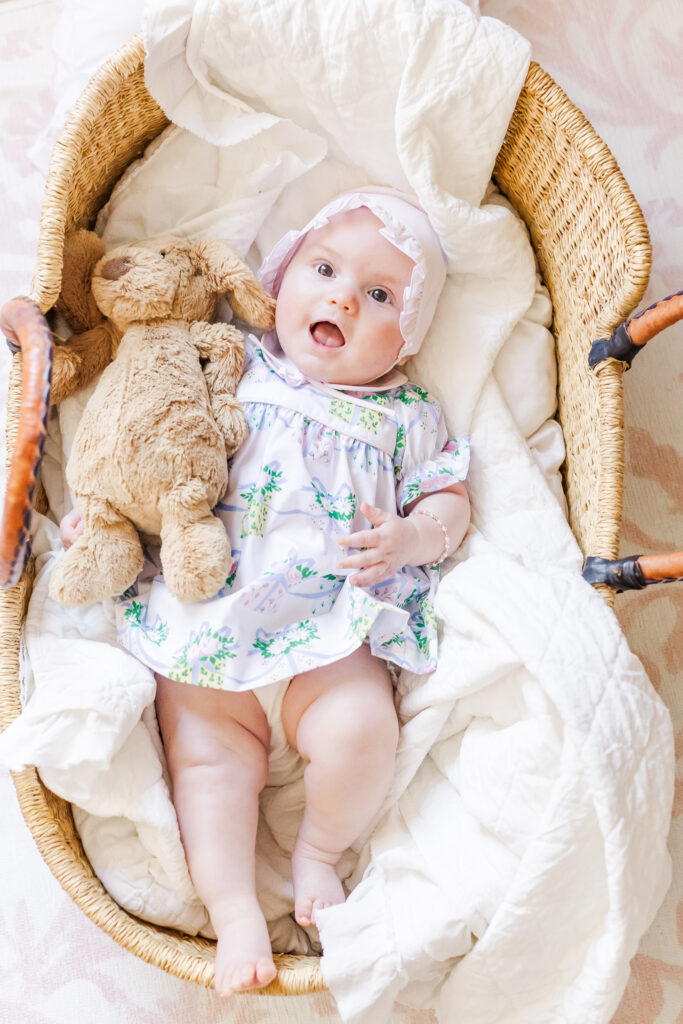Baby Ella peacefully resting in her crib surrounded by plush toys in her soft, pastel-colored nursery