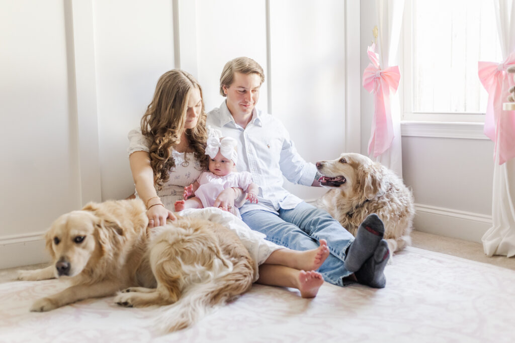 Family sitting on floor of nursery with little girl and 2 golden retrievers during 6 month milestone membership session with 5U Photography