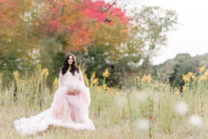 Mom standing in fall field during fall maternity session 