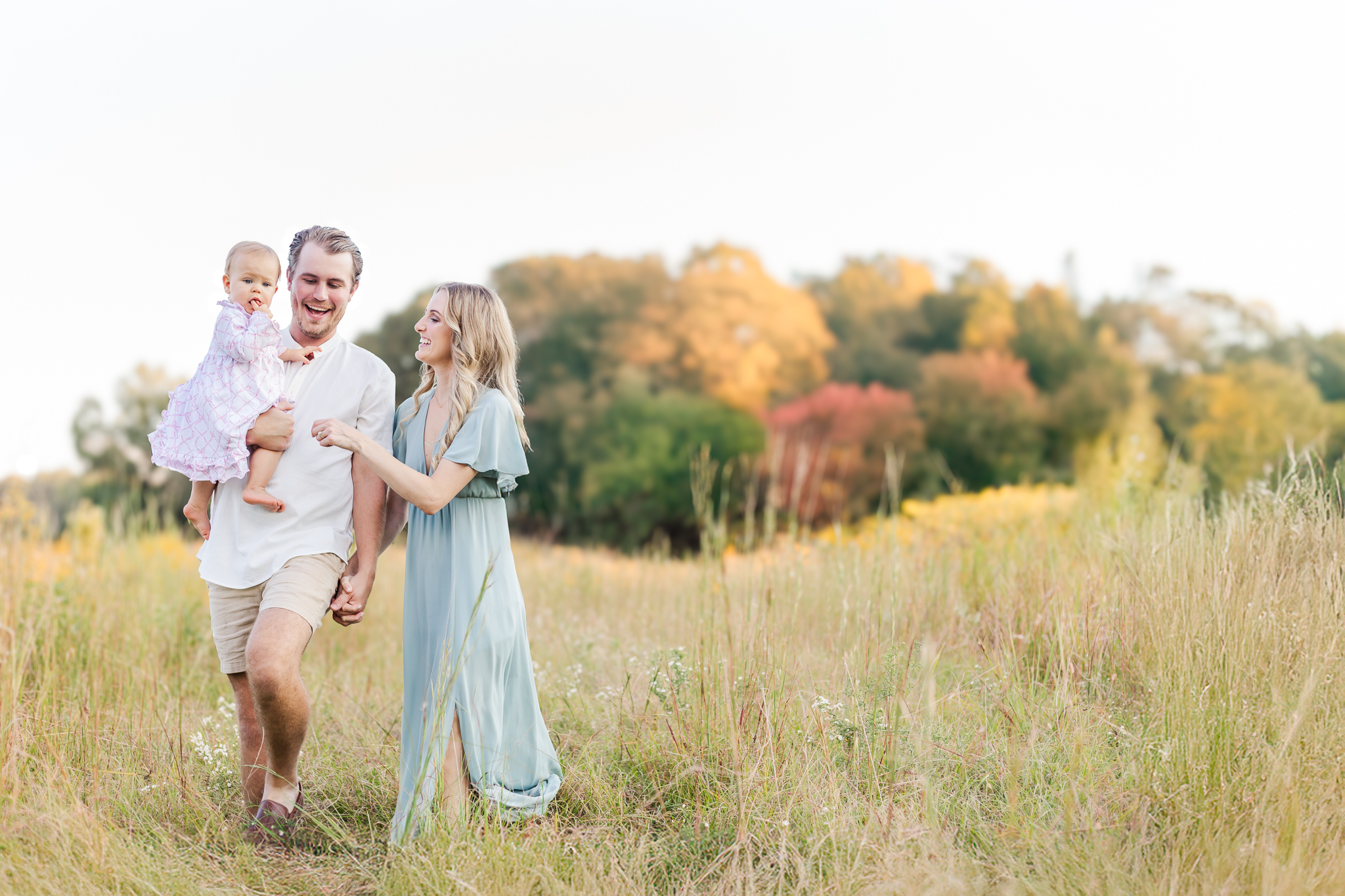 Family walking through a field at sunset wearing coordinated camel, cream, and sage green outfits styled with cable knit sweaters and boots for their fall family photos in birmingham alabama with 5U Photography