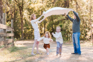 Mom and Dad playing with their 2 kids while laughing during fall family photos
