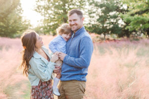 Mother in a flowy client closet gown and denim jacket holding her baby while the rest of the family coordinates in earthy neutrals during fall photo session