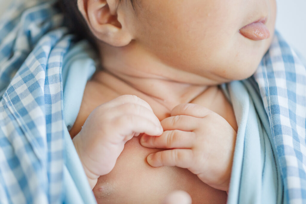 Newborn baby’s hands resting on chest with lips peeking out, captured during a Trussville, Alabama lifestyle newborn session.