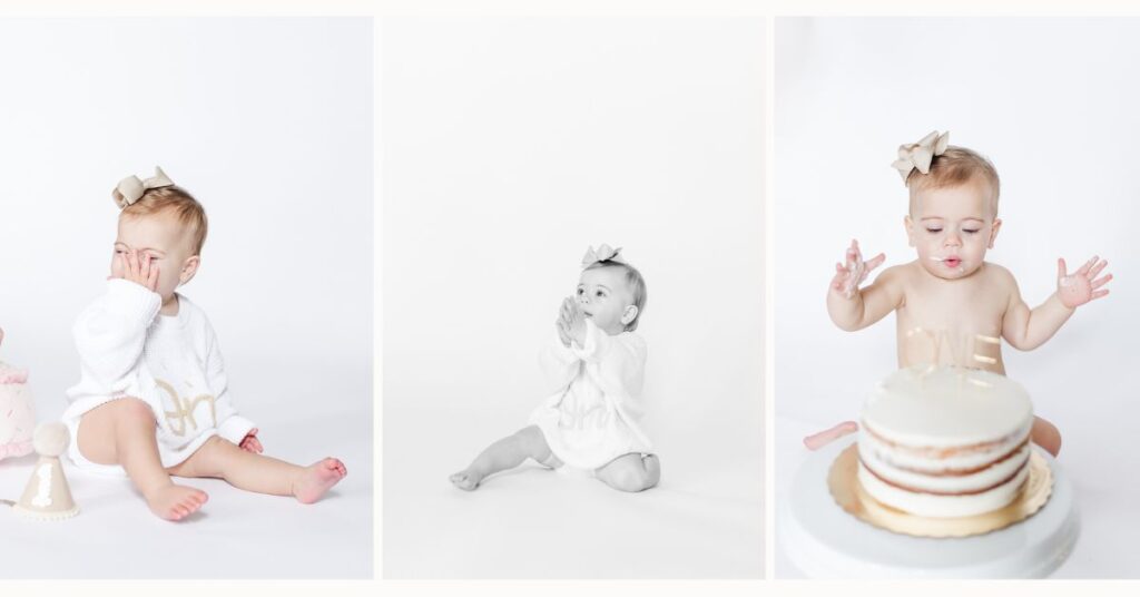 One year old baby girl sitting on a white backdrop during an in-home milestone session, wearing a soft sweater romper and bow, exploring cake smash moments in simple, timeless style.